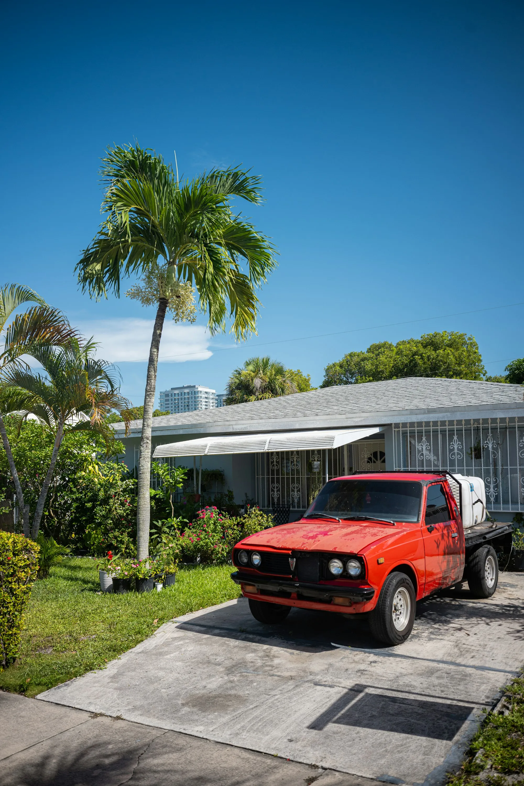 A pickup truck on a driveway in front of a house with palm trees