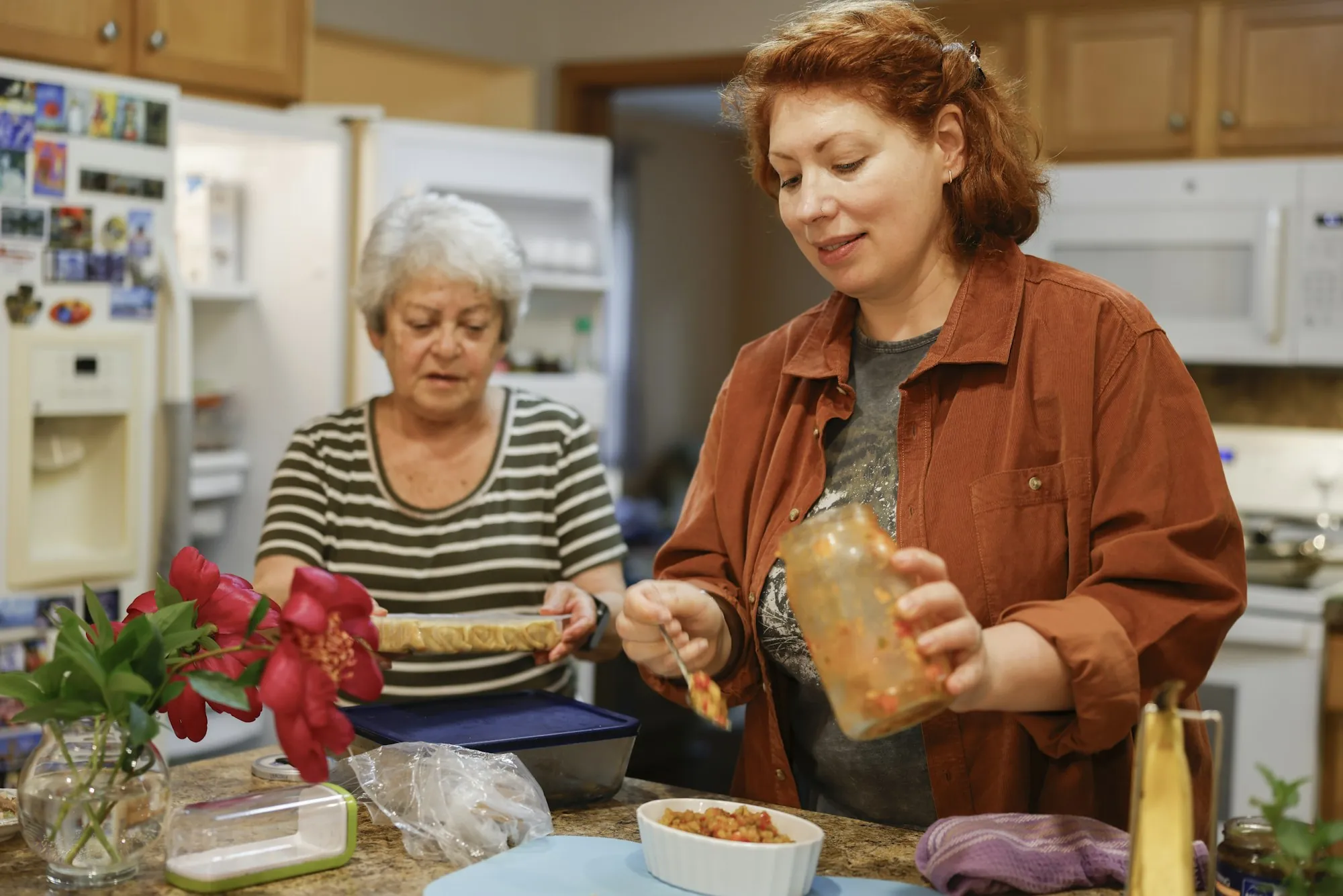 An older woman and a care worker preparing food together in a kitchen
